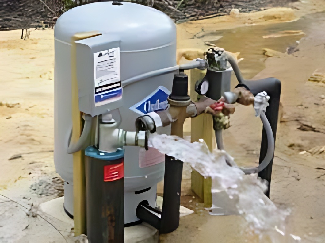 Water pump with visible hoses and flowing water, positioned on uneven ground. Relevant for discussions on water systems or plumbing solutions.
